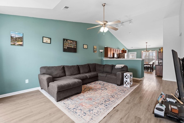 living area featuring light wood finished floors, visible vents, vaulted ceiling, baseboards, and ceiling fan with notable chandelier