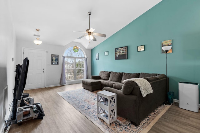 living room featuring a ceiling fan, vaulted ceiling, baseboards, and wood finished floors