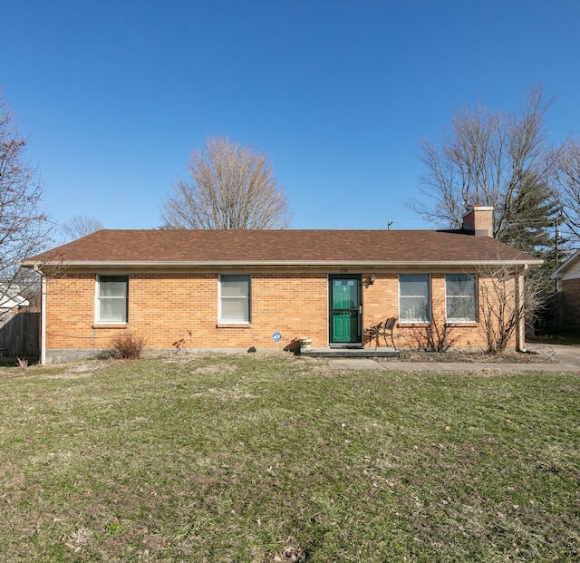 ranch-style house with a shingled roof, a front yard, brick siding, and a chimney