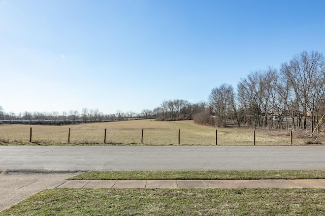 view of street featuring a rural view and sidewalks