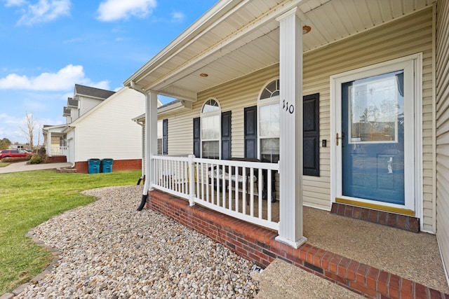 entrance to property with covered porch and a lawn