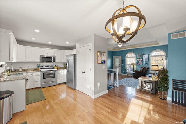 kitchen featuring stainless steel appliances, visible vents, an inviting chandelier, a sink, and light wood-type flooring