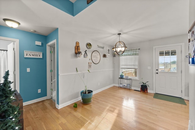 interior space with light wood-style floors, baseboards, and an inviting chandelier