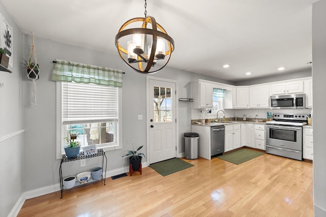 kitchen featuring light wood-type flooring, an inviting chandelier, appliances with stainless steel finishes, and white cabinets