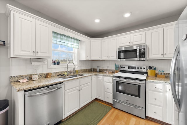 kitchen with appliances with stainless steel finishes, a sink, and white cabinets