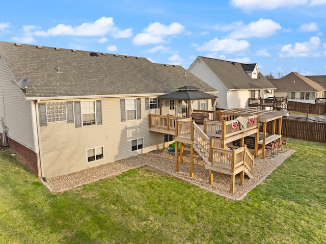 back of house featuring a deck, fence, roof with shingles, a lawn, and a residential view