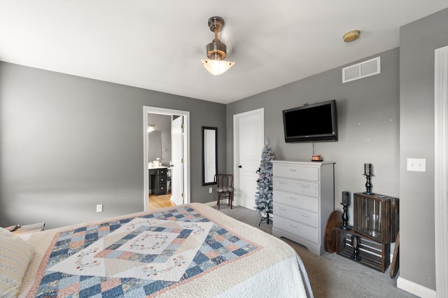 bedroom with connected bathroom, carpet flooring, visible vents, and baseboards