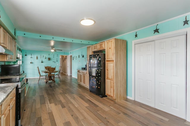 kitchen featuring light stone counters, wood finished floors, freestanding refrigerator, stainless steel range with electric stovetop, and light brown cabinets