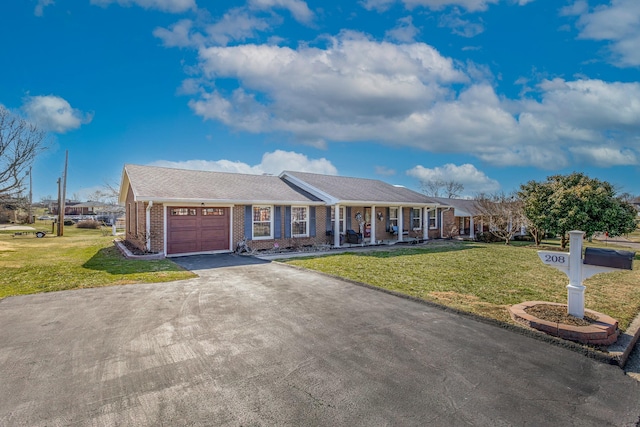 single story home featuring driveway, brick siding, an attached garage, covered porch, and a front yard