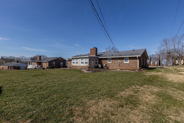 back of property with a chimney, a lawn, and brick siding