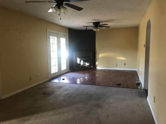 unfurnished living room featuring a large fireplace, a textured ceiling, a ceiling fan, and baseboards