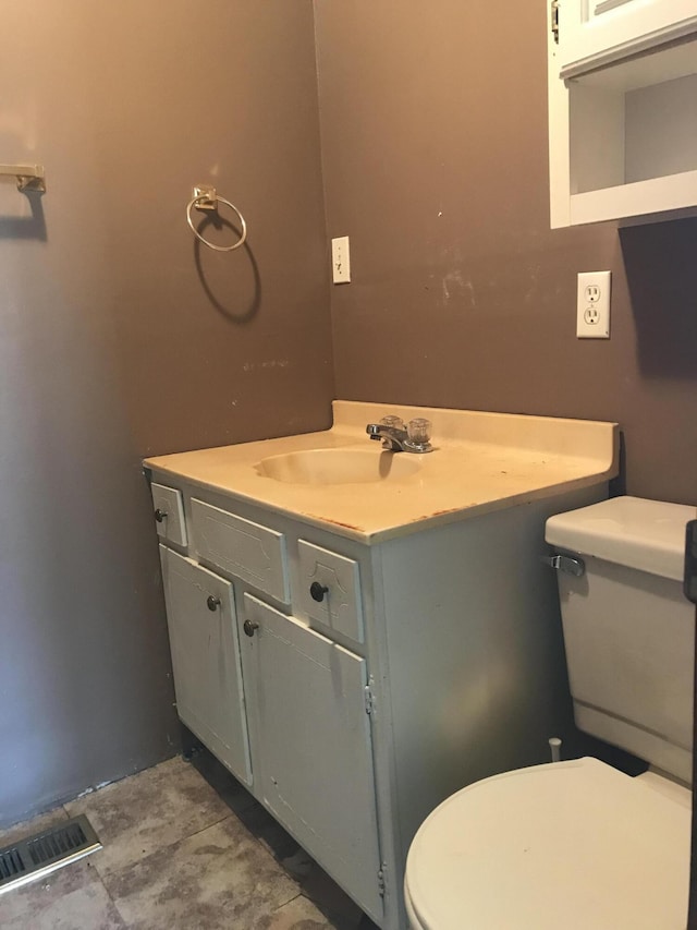 half bathroom featuring toilet, visible vents, and vanity