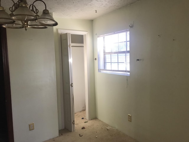 unfurnished bedroom featuring a textured ceiling and a notable chandelier