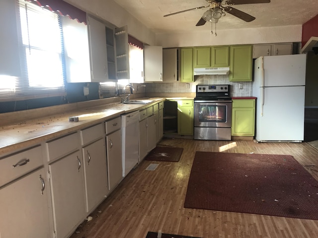 kitchen featuring white appliances, wood finished floors, under cabinet range hood, green cabinets, and a sink