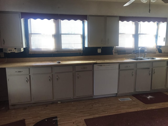 kitchen with light countertops, dishwasher, a sink, and wood finished floors