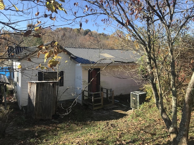 rear view of property with central air condition unit, metal roof, and entry steps