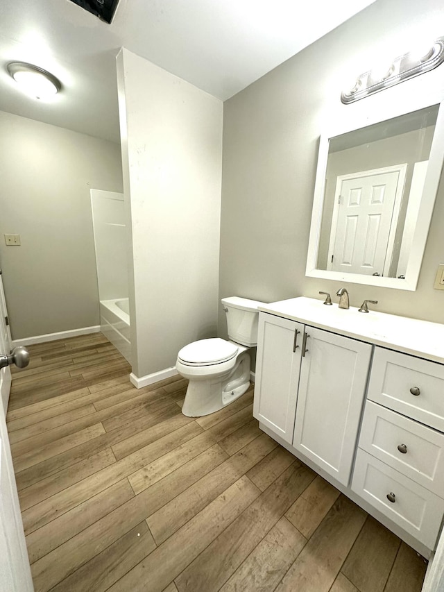 bathroom with toilet, baseboards, wood finished floors, and vanity
