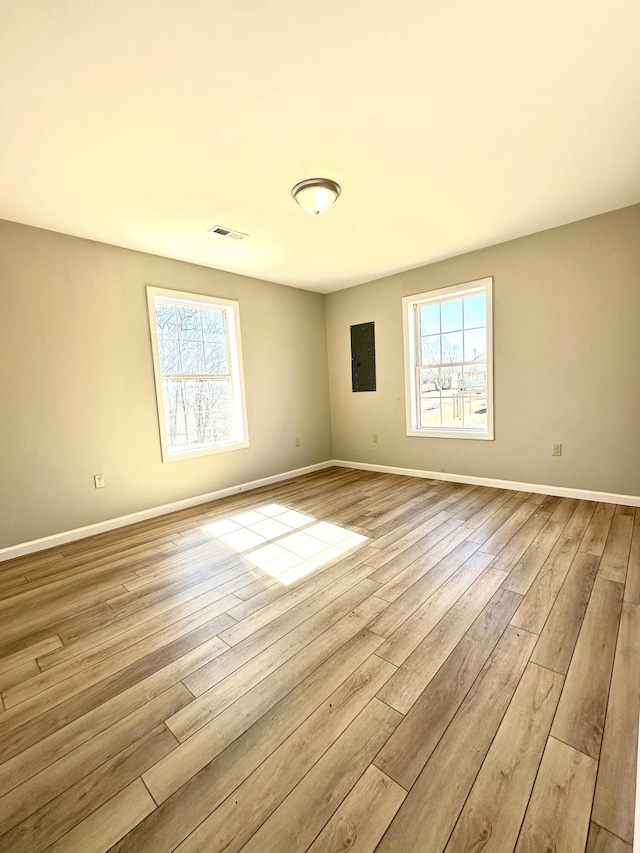 empty room featuring a wealth of natural light, wood finished floors, and visible vents
