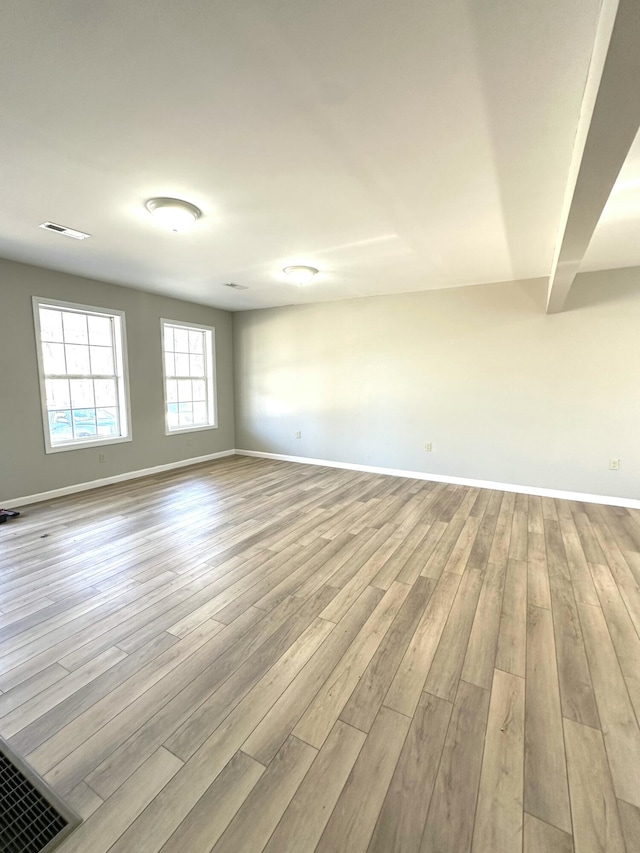 unfurnished room featuring light wood-style flooring, visible vents, and baseboards