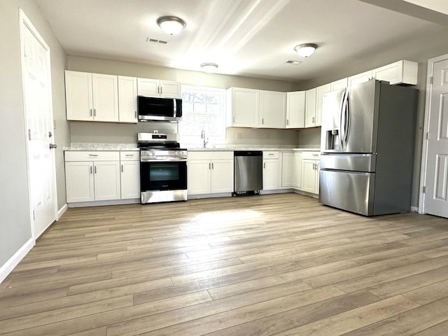 kitchen featuring visible vents, appliances with stainless steel finishes, white cabinets, and light wood-style flooring