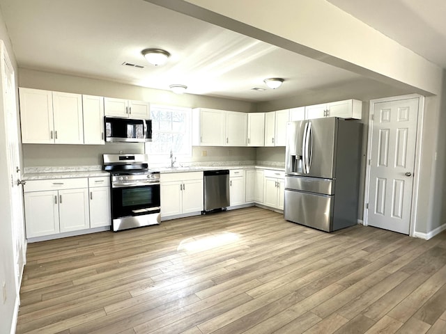 kitchen featuring light wood-style flooring, visible vents, white cabinetry, light countertops, and appliances with stainless steel finishes