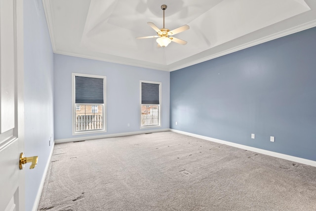 carpeted empty room featuring baseboards, visible vents, ceiling fan, a tray ceiling, and crown molding