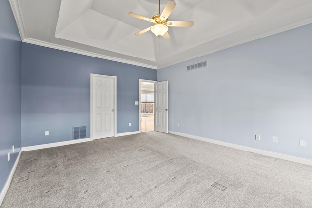 carpeted spare room featuring a raised ceiling, visible vents, ornamental molding, ceiling fan, and baseboards