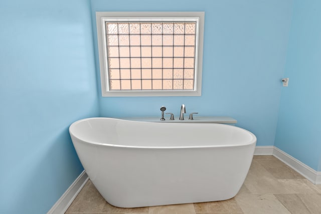 full bathroom featuring a soaking tub and baseboards