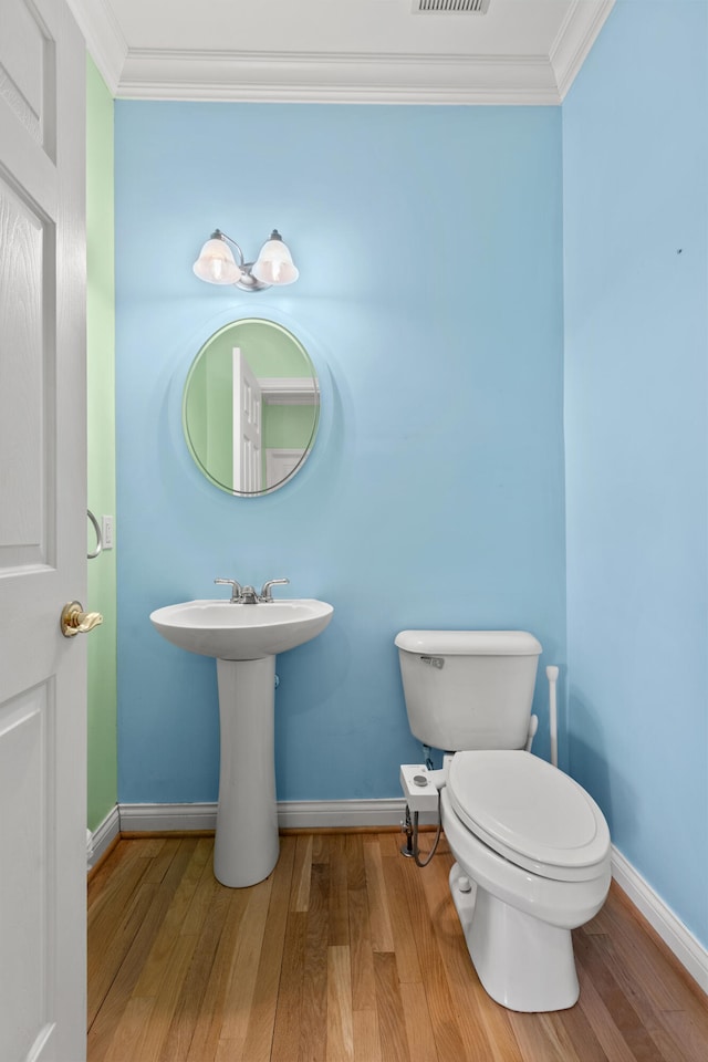 bathroom featuring baseboards, ornamental molding, and wood finished floors