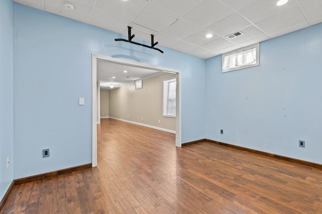 interior space with baseboards, visible vents, a drop ceiling, wood finished floors, and recessed lighting