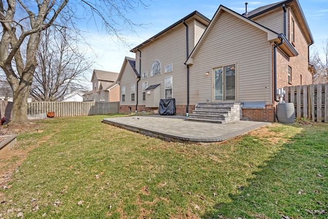 back of property with entry steps, a lawn, a fenced backyard, a patio area, and brick siding