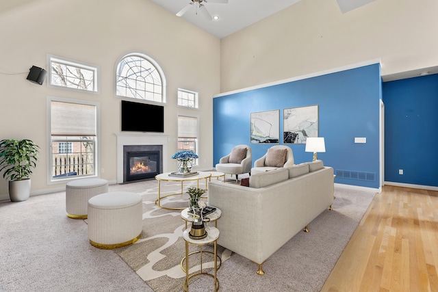 living area with a towering ceiling, plenty of natural light, and a glass covered fireplace