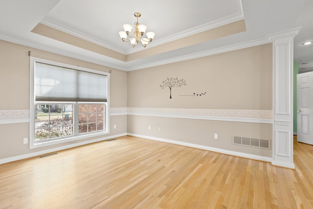 unfurnished room with a tray ceiling, light wood-style flooring, visible vents, and an inviting chandelier