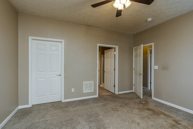 unfurnished bedroom with a textured ceiling, carpet, visible vents, and baseboards