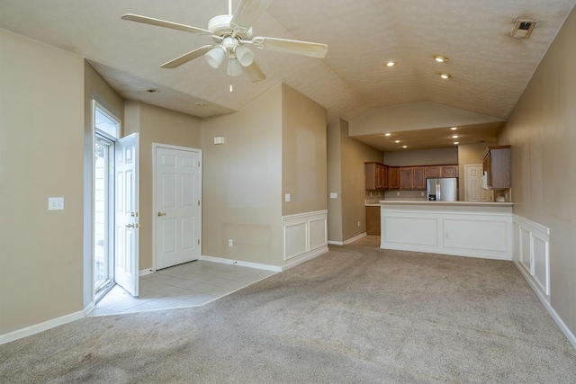 unfurnished living room featuring light tile patterned flooring, light carpet, visible vents, a ceiling fan, and vaulted ceiling