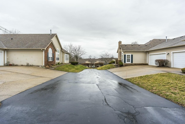 view of side of home featuring a garage, a chimney, concrete driveway, and brick siding