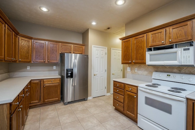 kitchen with recessed lighting, white appliances, light countertops, backsplash, and brown cabinetry