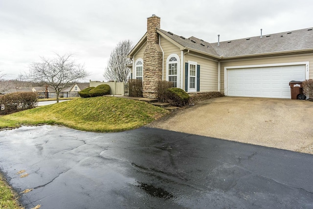 view of side of property with a shingled roof, concrete driveway, a chimney, an attached garage, and fence