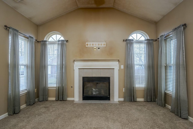 unfurnished living room with vaulted ceiling, a healthy amount of sunlight, a fireplace, and carpet