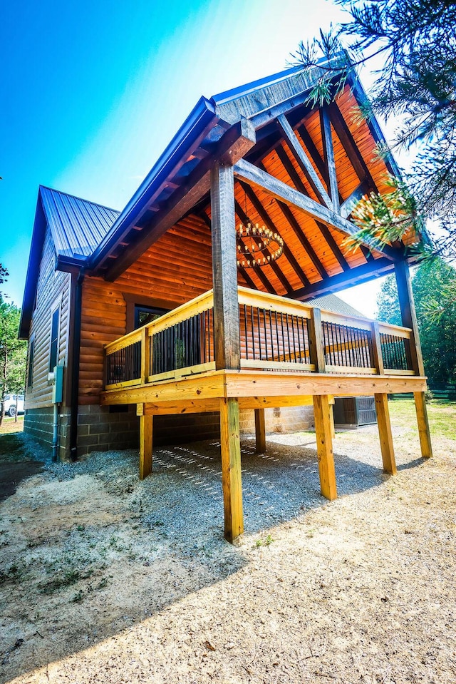 view of side of home with an attached carport, faux log siding, and metal roof