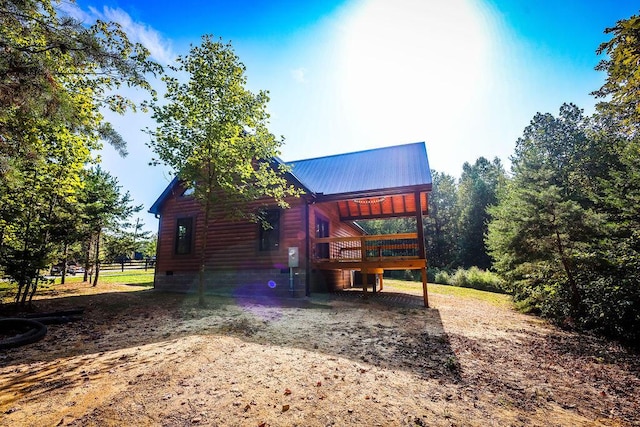 view of side of home featuring metal roof, a wooden deck, and driveway