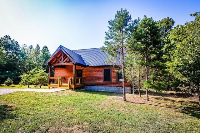 view of front of house with metal roof, a front lawn, and log veneer siding