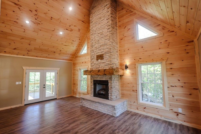 unfurnished living room with a wealth of natural light, wood ceiling, a stone fireplace, and french doors