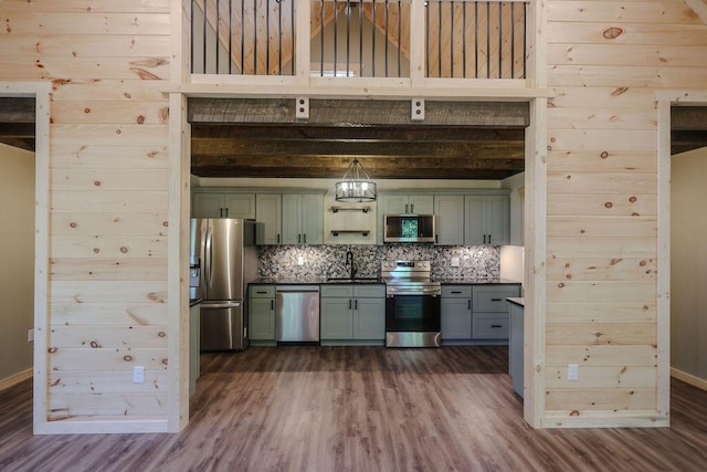 kitchen featuring appliances with stainless steel finishes, a sink, decorative backsplash, and green cabinets