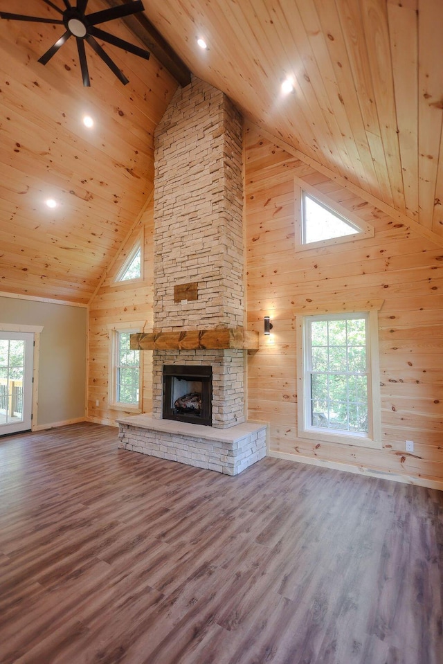 unfurnished living room featuring a fireplace, wood ceiling, wood walls, wood finished floors, and high vaulted ceiling