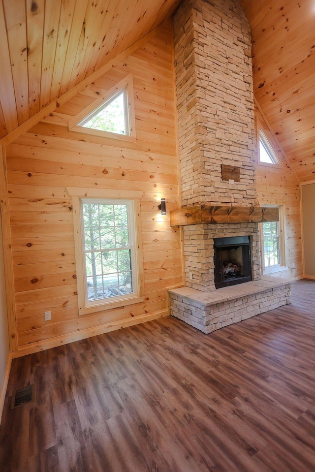 unfurnished living room with a wealth of natural light, wood ceiling, visible vents, and a stone fireplace