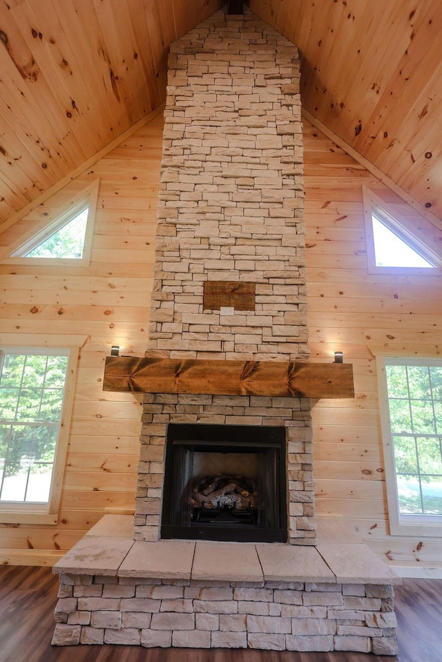 interior details with wooden ceiling, wood walls, and a stone fireplace