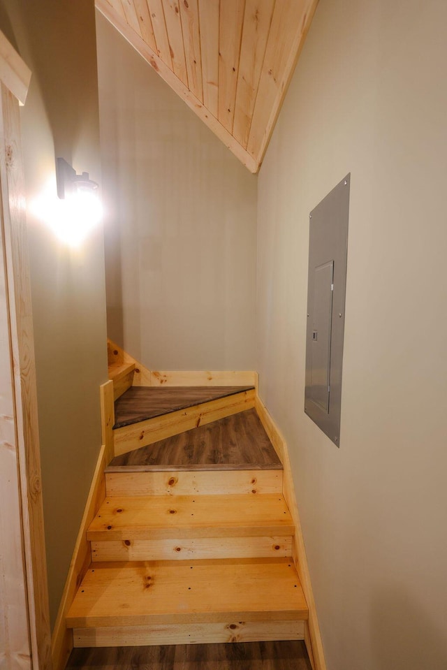 stairs with wood ceiling, electric panel, and vaulted ceiling