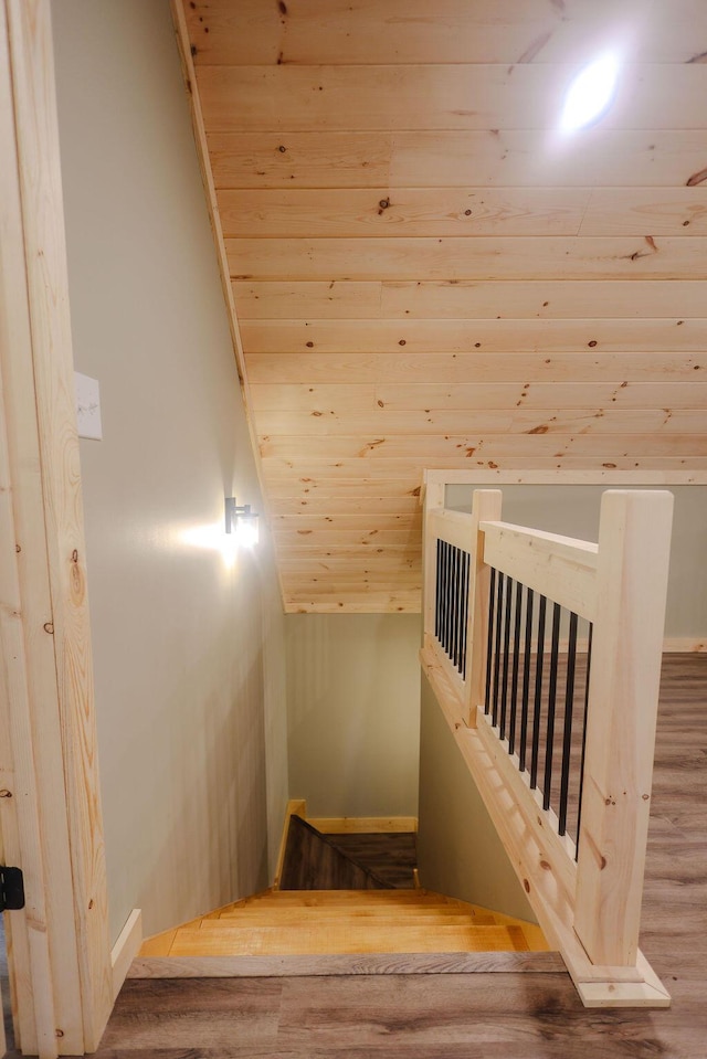 stairway featuring lofted ceiling, wood ceiling, and wood finished floors