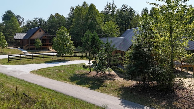 view of community featuring a lawn, driveway, and fence